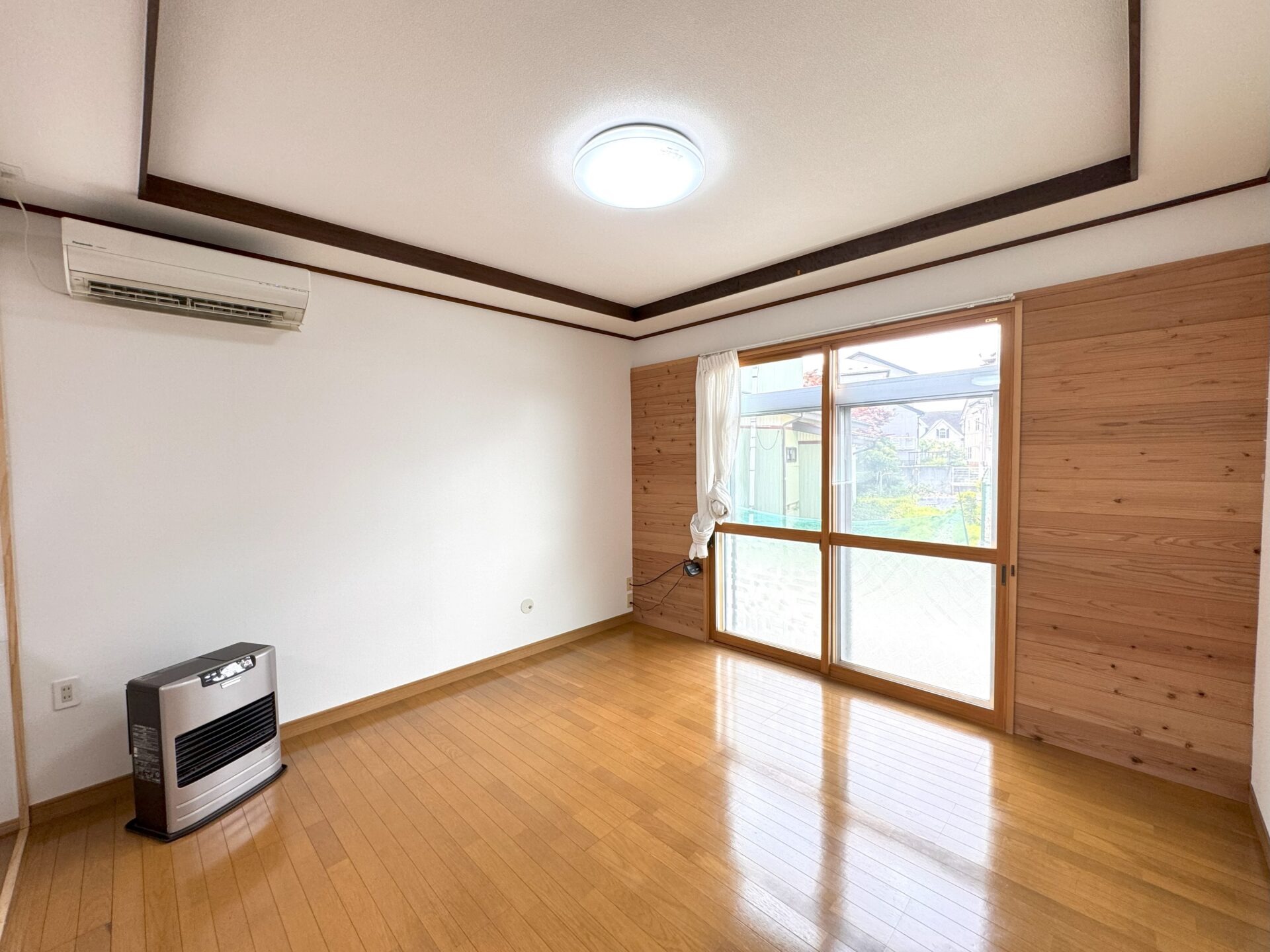 居心地の良い洋室。木製の床、引き戸、暖房、窓から見える外の景色。